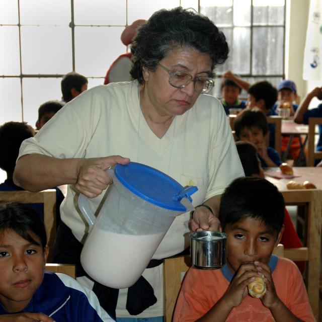 Blanca Urrutia serves food to children in Collique, Peru